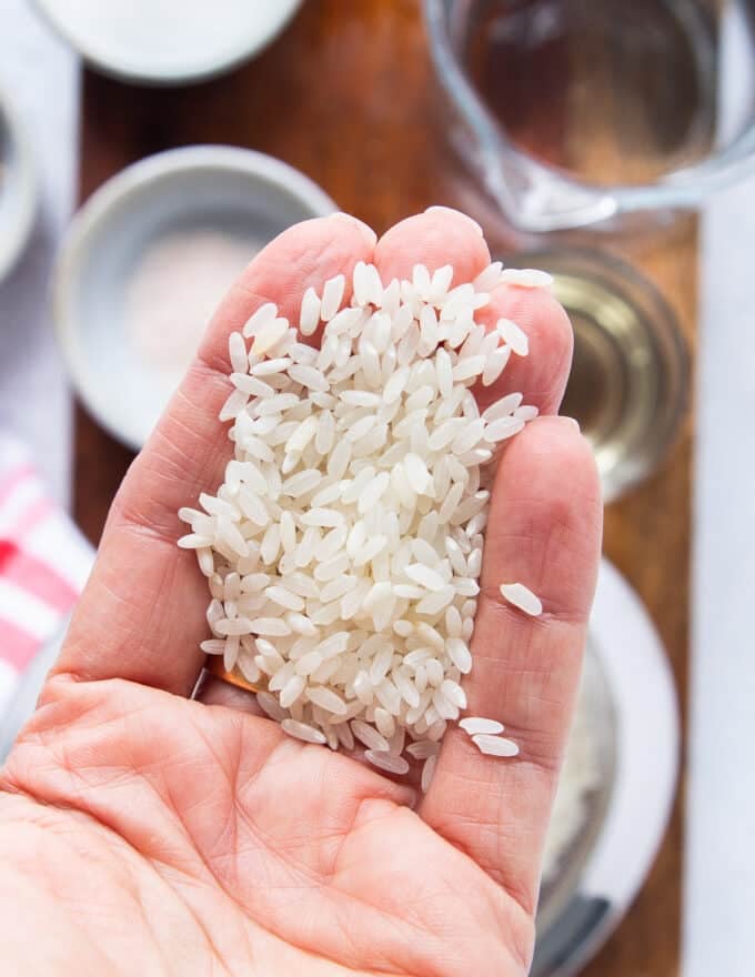 A hand holding short grain rice showing the best japanese rice used or short grain rice to make the best sushi rice