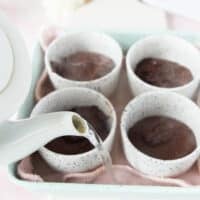 hot boiling water from a kettle being poured in the baking dish to form a water bath