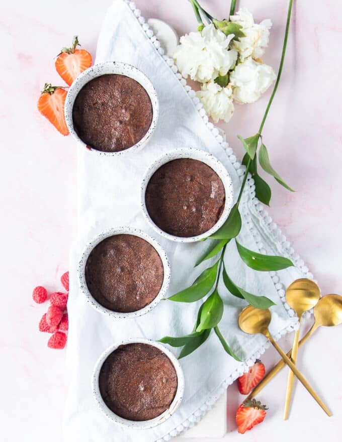 the baked brownie pudding on a marble with berries for serving and some spoons 