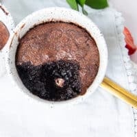 close up of a brownie pudding with the spoon taken off showing the contrast in texture with the crackly tops and soft molten centers
