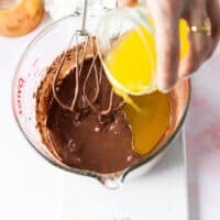 melted and cooled butter is slowly drizzled to the side of the bowl to finish the brownie batter