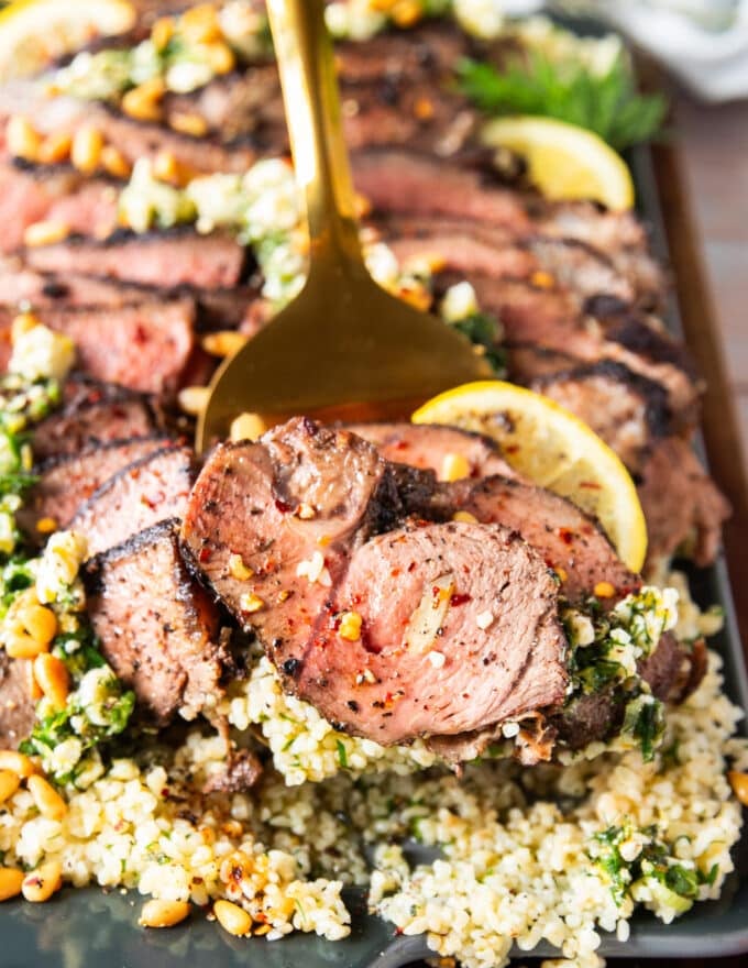 close up of a serving of butterflied leg of lamb on a slotted spoon showing the texture close up 