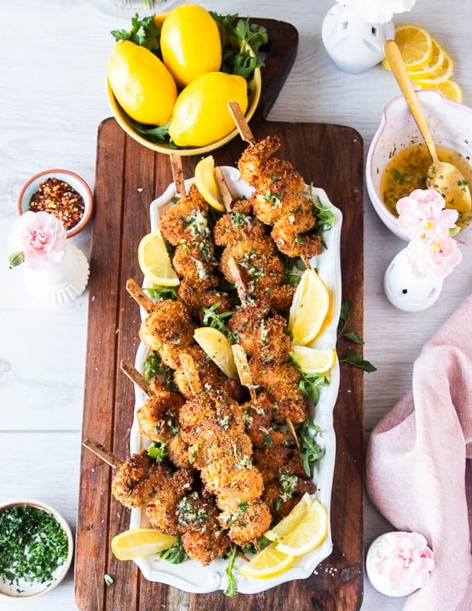 A plate of chicken spiedini garnished with lemon wedges and drizzled with garlic butter