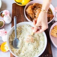 chicken pieces coated in bread crumbs pressed down and being skewered for chicken spiedini