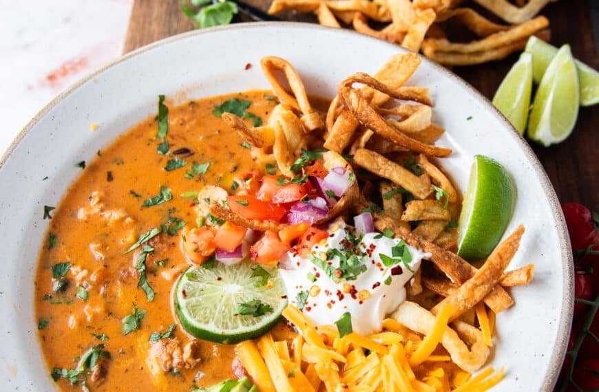 one bowl of perfect chicken taco soup close up topped with tortillas, avocado, sour cream, cilantro and cheese
