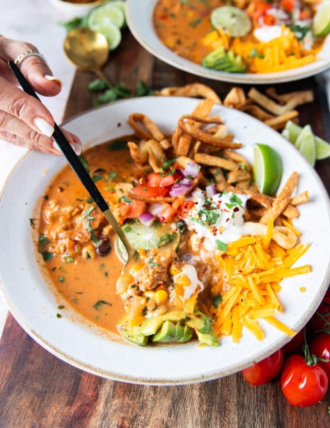 A spoon eating some chicken taco sopu showing the creamy soup and the many toppings