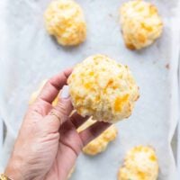 A hand holding one drop biscuit fresh out of the oven close up showing the perfect golden brown and fluffy texture