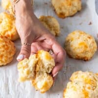 A hand holding a broken up drop biscuit showing the perfect texture inside