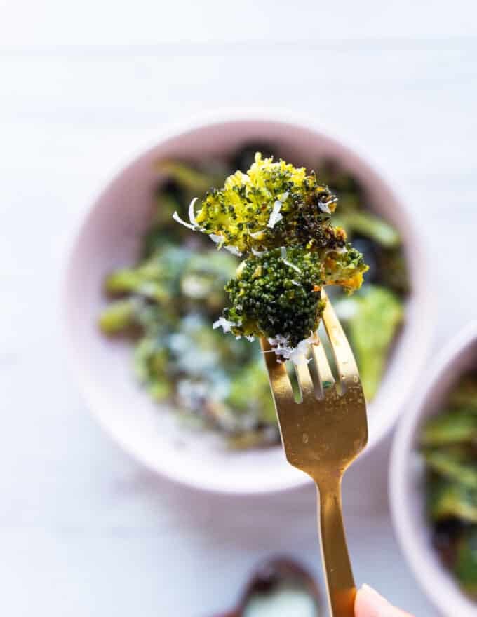 A fork holding an air fryer broccoli piece close up showing the crisp and perfectly cooked broccoli 