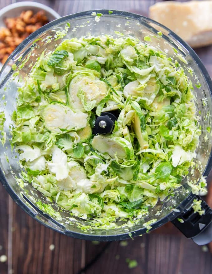 fully shredded brussel sprouts in the bowl of a food processor 