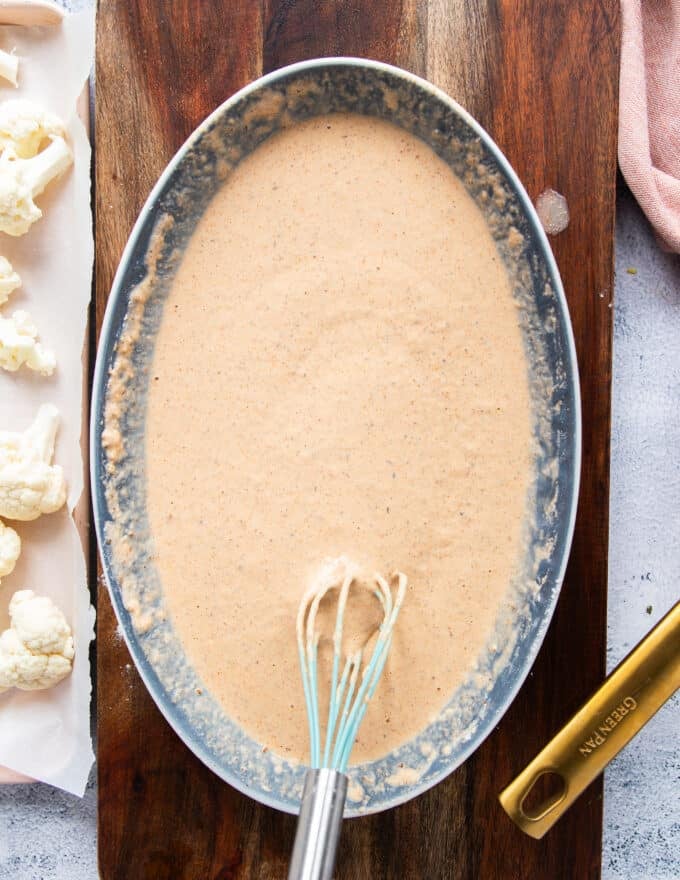 water is added and the batter is ready in a shallow bowl to make buffalo cauliflower bites 