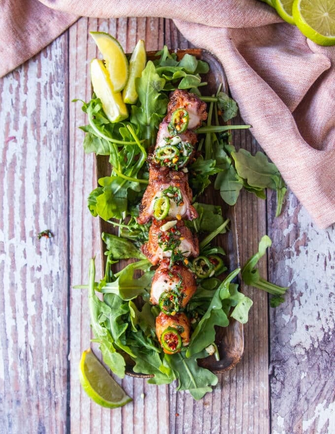 A plate of fried octopus served over arugula and topped with chilies and lemon