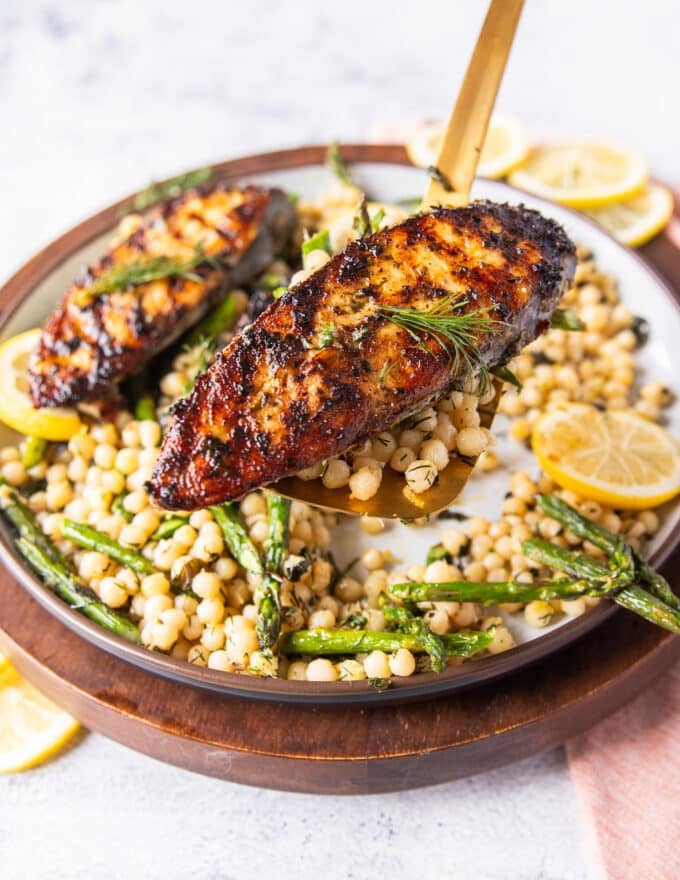 A spatula holding close up a cooked kingfish steak showing the golden grill mark on the fish 