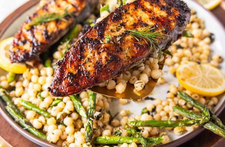 A spatula holding close up a cooked kingfish steak showing the golden grill mark on the fish