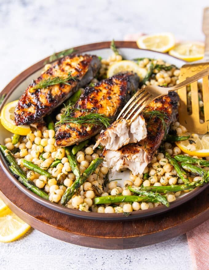 fork breaking apart a king mackerel steak showing the texture on the side and crispy skin 
