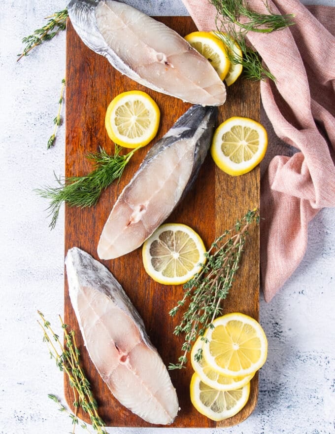 Ingredients to make kingfish steaks including a few kingfish fish on a board and small marinade ingredients on another board 