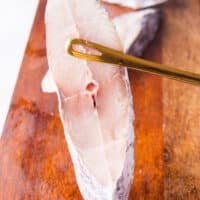 A hand holding a kingfish steak close up showing the texture and structure of the kingfish