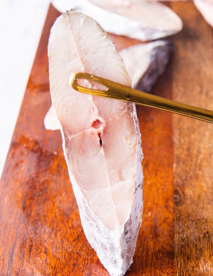 A hand holding a kingfish steak close up showing the texture and structure of the kingfish