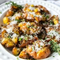 smashed potatoes on a serving plate close up showing the fluffy inside and crisp outside