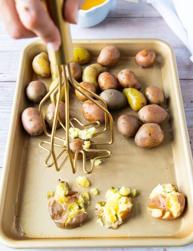 A masher used to smash the potatoes one at a time on the baking sheet