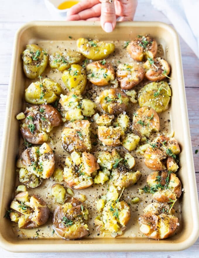 Read to roast tray of smashed potatoes with herbs and seasoning 