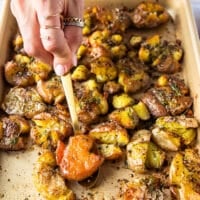 A spoon holing a flipped up potato showing the golden crust and crisp edges with fluffy center