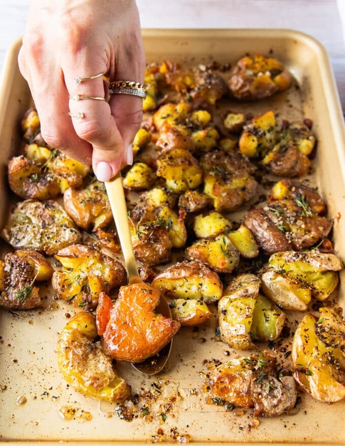 A spoon holing a flipped up potato showing the golden crust and crisp edges with fluffy center
