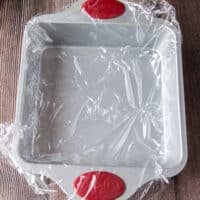 lined square pan with plastic wrap ready for the rice to go on top
