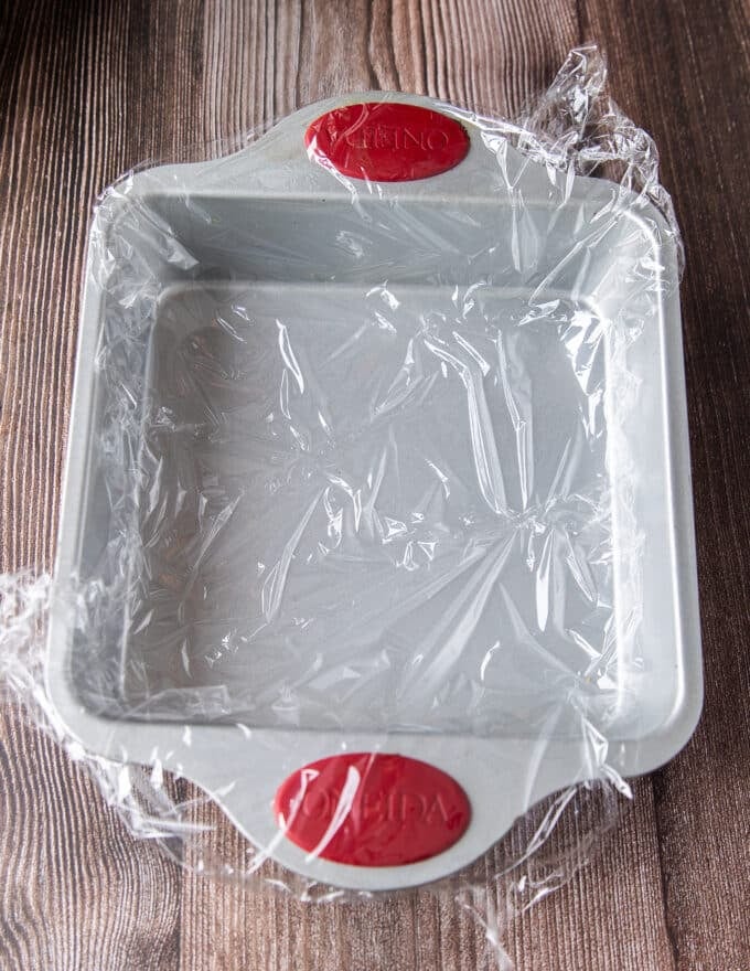 lined square pan with plastic wrap ready for the rice to go on top