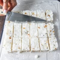 A knife cutting up the rice into rectangles for frying