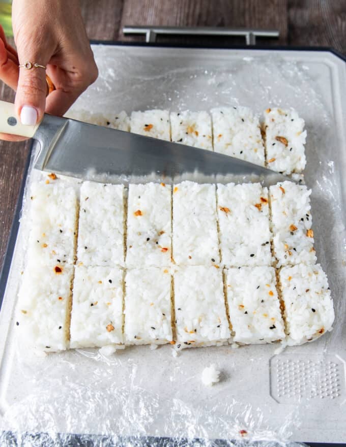 A knife cutting up the rice into rectangles for frying 