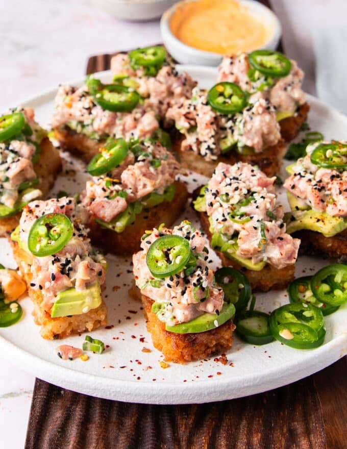 A full plate of assembled spicy tuna crispy rice on a plate with extra jalapenos on the side and a spicy mayo dip