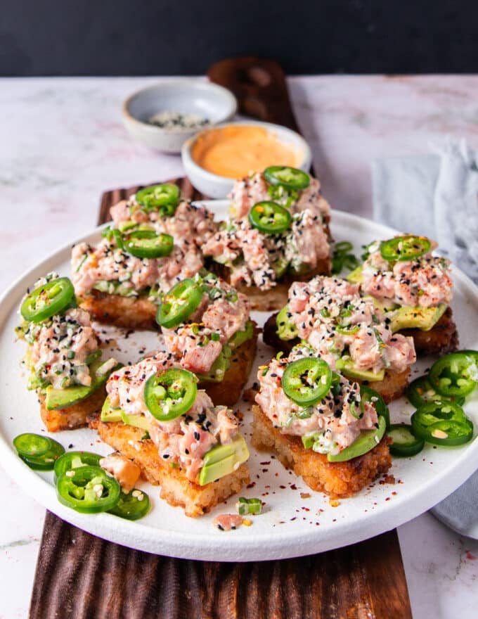 Spicy Tuna Crispy Rice on a large serving plate topped with sesame seeds and more jalapeno slices