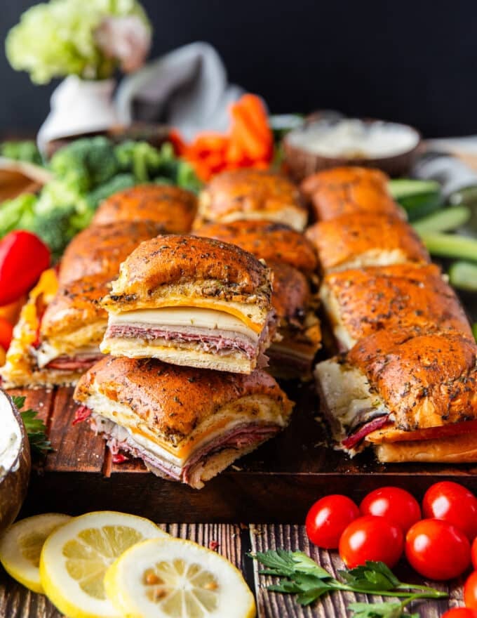 close up of stacked roast beef sliders on a large board with bowls of creamy dips