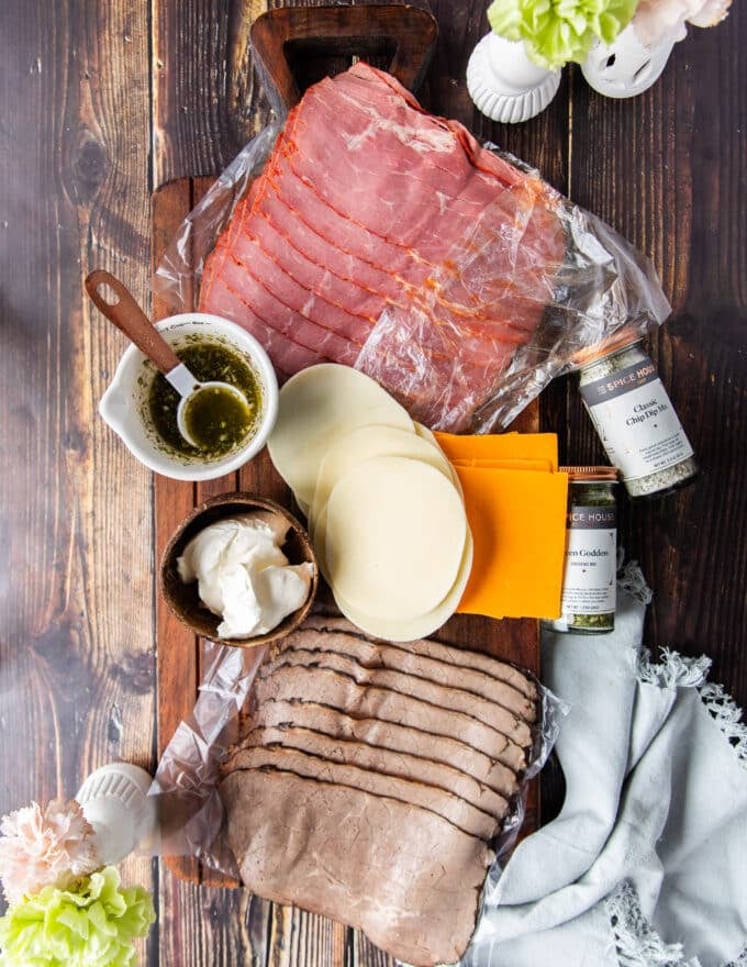 Ingredients for roast beef sliders on a board , Thinly sliced roast beef, cheeses and sauces