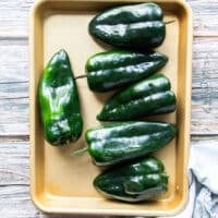 poblano peppers on a baking sheet with some olive oil on the side and salt optional