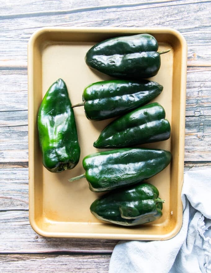 poblano peppers on a baking sheet with some olive oil on the side and salt optional