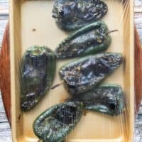 charred peppers covered with plastic wrap to steam