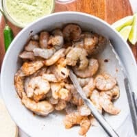 raw shrimp with seasoning and olive oil in a bowl ready to cook