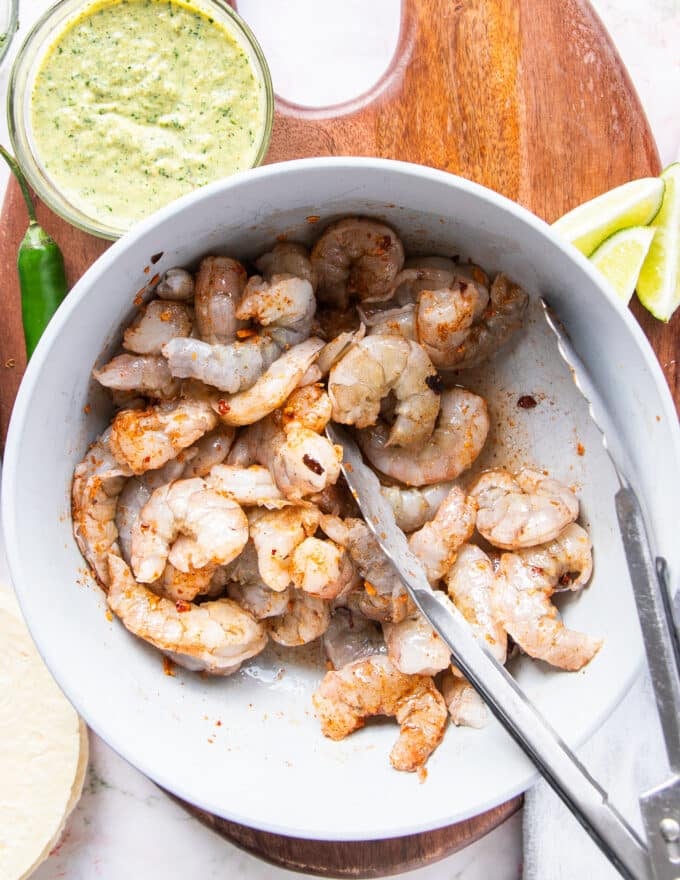 raw shrimp with seasoning and olive oil in a bowl ready to cook