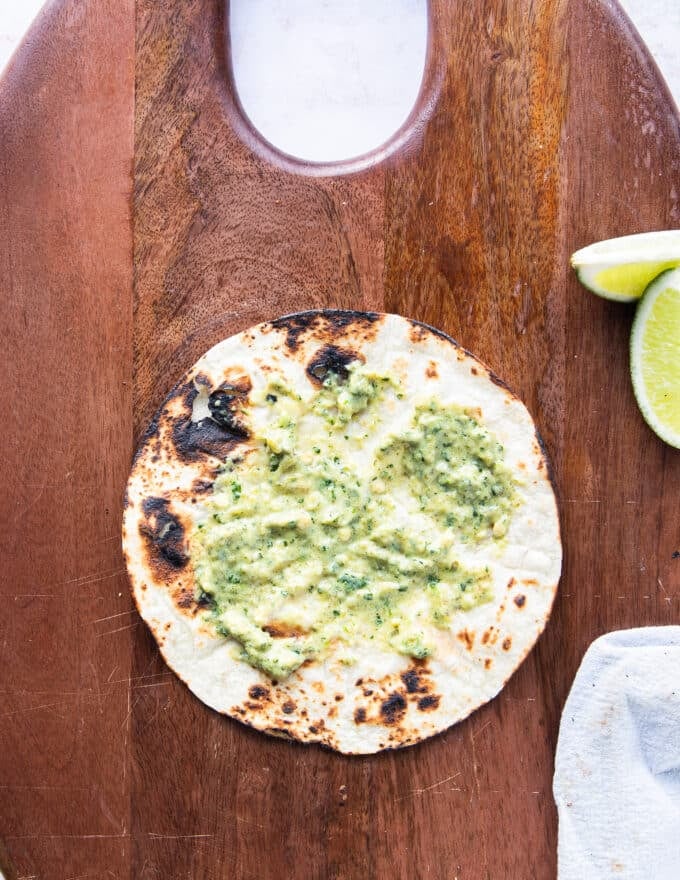 charred tortilla with a spread of poblano sauce and taco sauce