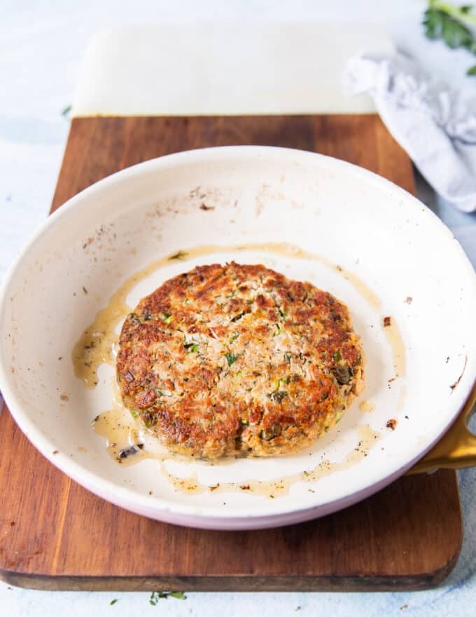 Tuna patty flipped in a skillet to show the golden tuna burger cooking