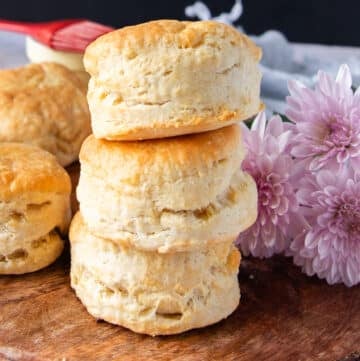 Stacks of air fryer biscuits on a wooden board show how tall and fluffy the biscuits are