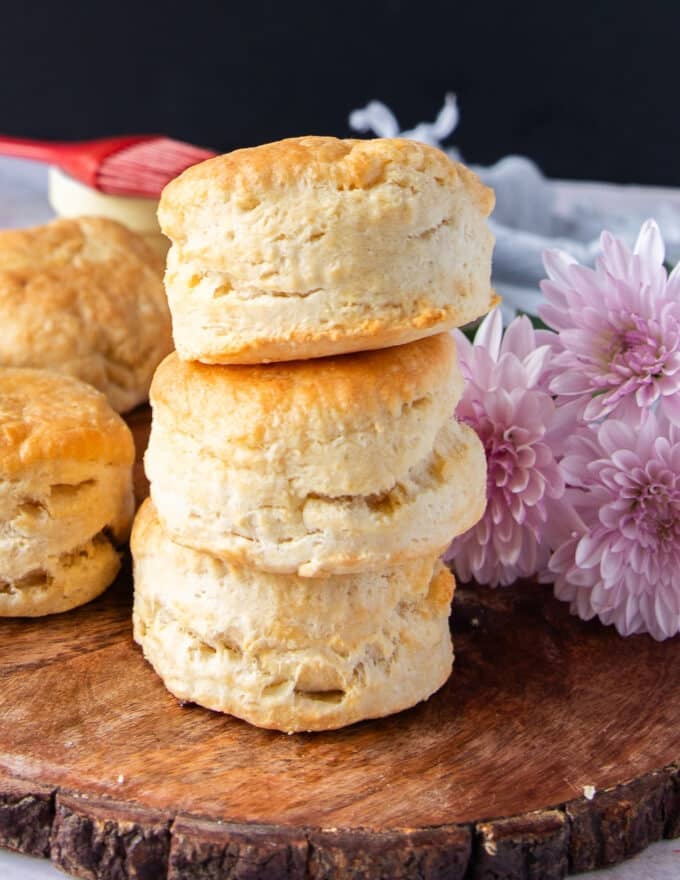 Stacks of air fryer biscuits on a wooden board show how tall and fluffy the biscuits are