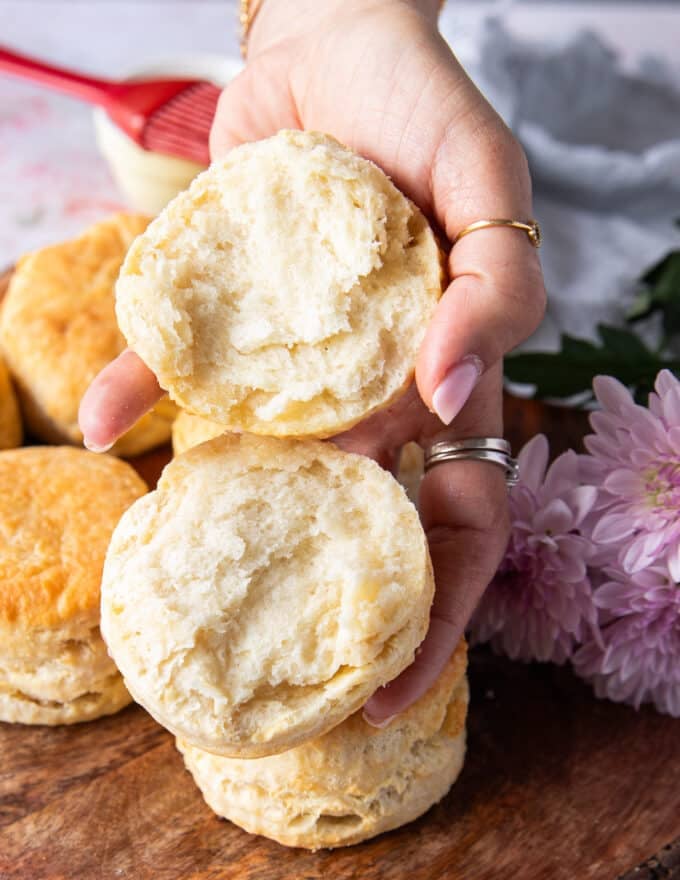 A hand holding an air fryer biscuit cut in half showing the fluffy interior