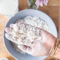 A hand holding the butter incorporated into the flour showing the coarse crumb texture ready to add the buttermilk