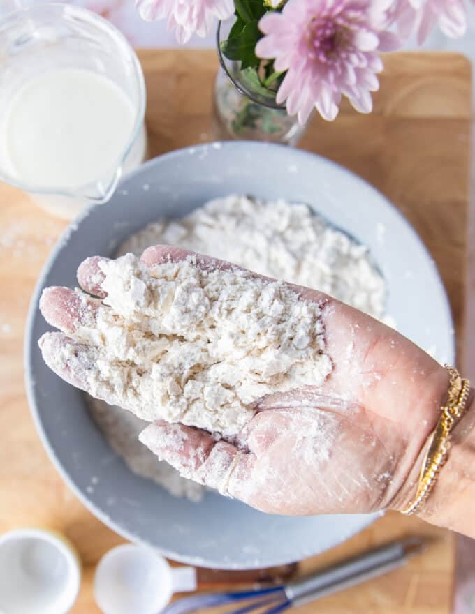 A hand holding the butter incorporated into the flour showing the coarse crumb texture ready to add the buttermilk