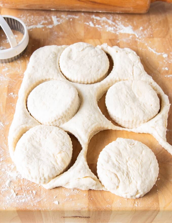 cut up pieces of biscuits from the biscuit dough on a board