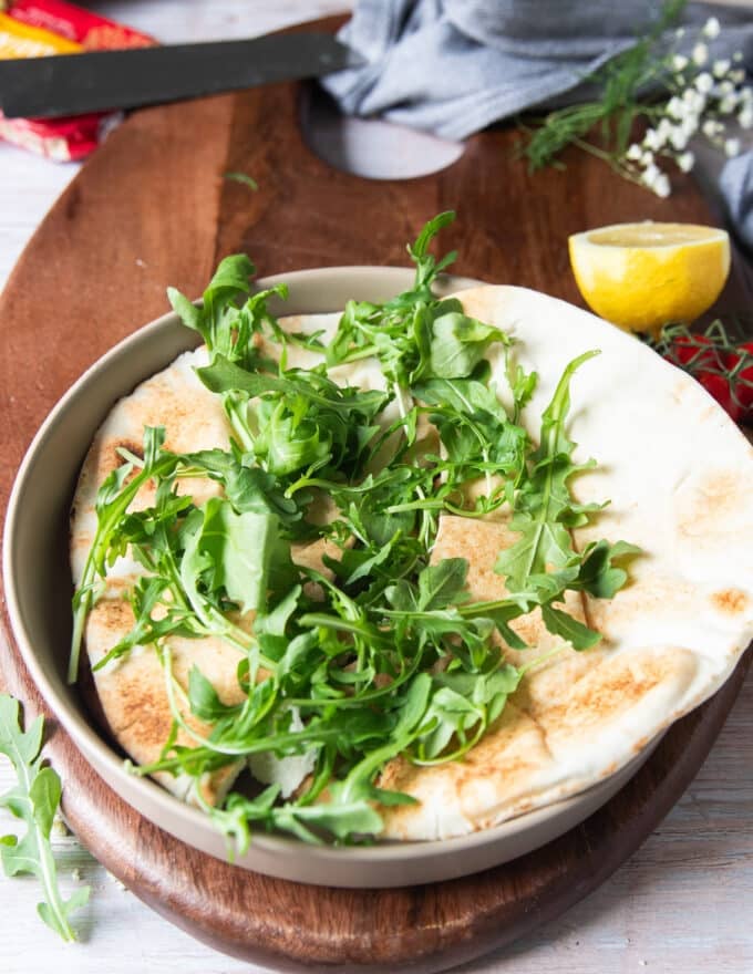 building a sardines bowl starts with a layer of bread and then some arugula on top