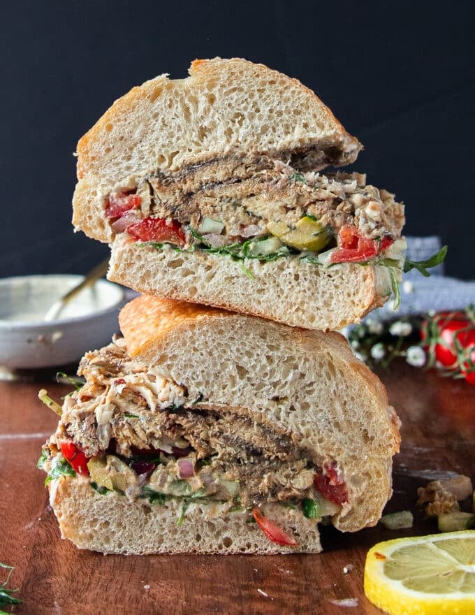 Layered sardine sandwich with fresh ingredients and sauces